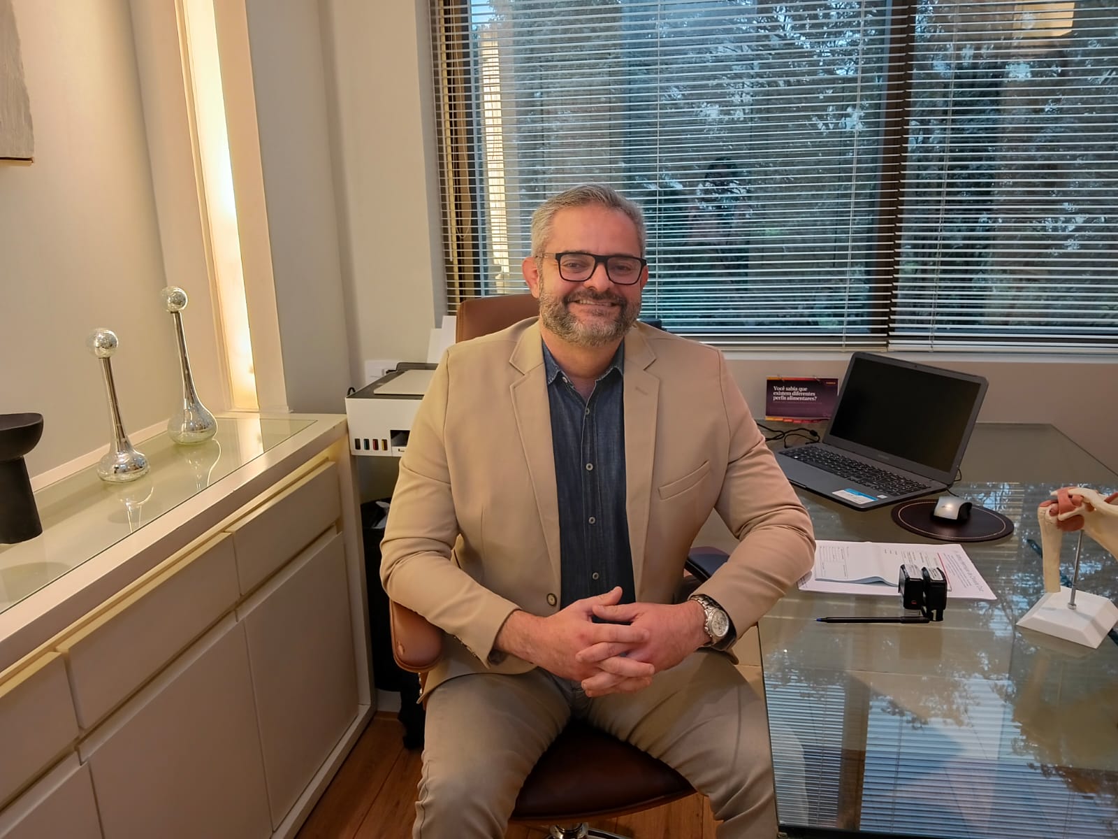 Dr. Arthur Henrique de Oliveira Cruz sentado à mesa em seu consultório na Barra da Tijuca